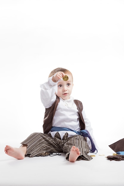 Happy caucasian little boy, dressed as a pirate Playing with coins and confetti. little boy and costumes concept.