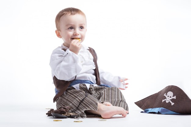 Счастливый кавказской маленький мальчик, одетый как пират, играя с монетами и конфетти. концепция маленького мальчика и костюмов.