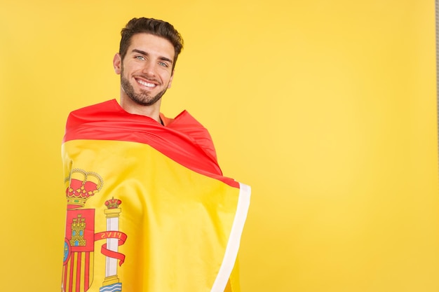 Happy caucasian man wrapping with a spanish national flag