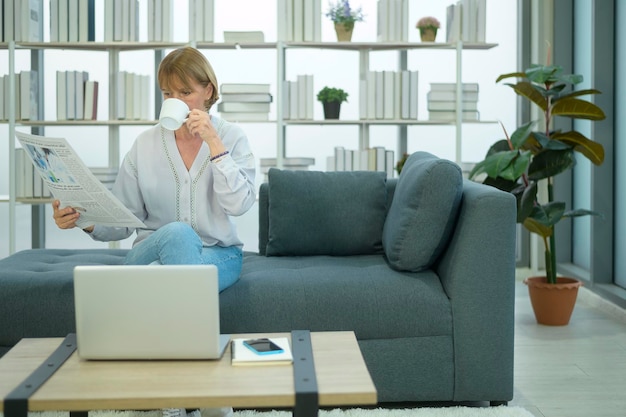 Happy  Caucasian senior woman  is relaxing , reading newspaper in living room