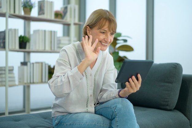 A happy Caucasian senior woman video call to family or friends, relax at home, smiling healthy senior retired grandparents, older grandparent technology concept