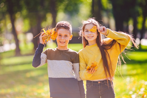 Happy Caucasian siblings enjoying in autumn day in park