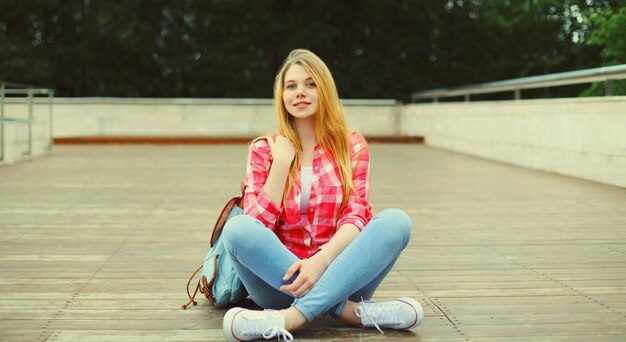 happy caucasian teenager girl with backpack posing on city street