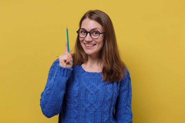 Happy caucasian woman in eyeglasses having idea pointing with pencil up