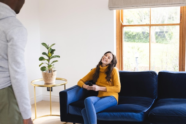 Photo happy caucasian woman sitting on sofa using smartphone at home