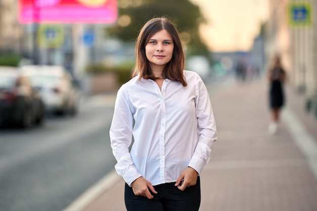 Happy caucasian young woman stands outdoors on city street