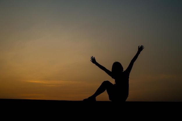 Photo happy celebrating winning success woman at sunset or sunrise standing elated with arms raised up above her head