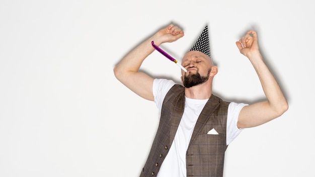 Happy celebration Birthday man Holiday fun Party joy Excited funny guy casual look wearing festive hat blowing whistle dancing isolated white copy space