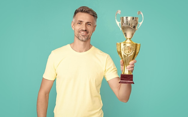 Foto happy champion man celebrate victory award isolated on blue champion man celebrate victory with award in studio champion man celebrate award victory photo of champion man celebrate victory