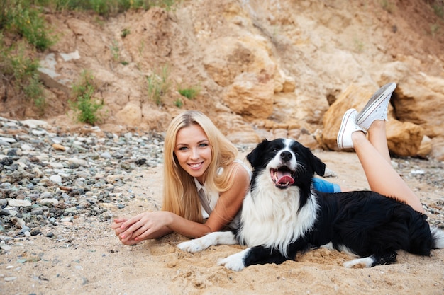 ビーチで犬と幸せな魅力的な若い女性