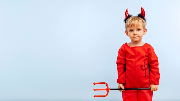 Photo happy cheerful boy in devil costume with trident on blue background