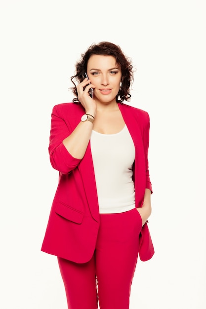 Happy, cheerful businesswoman talking on mobile phone in pink suit