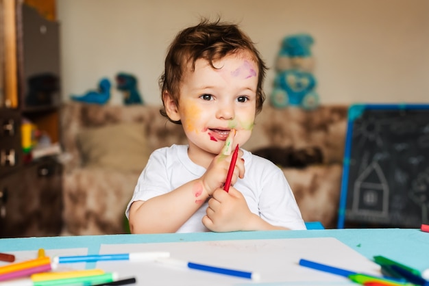 A happy cheerful child draws with a felt tip pen in an album using a variety of drawing tools.