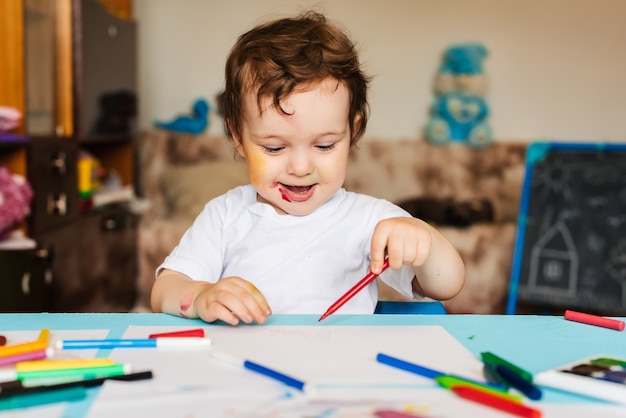 A happy cheerful child draws with a felt tip pen in an album using a variety of drawing tools.