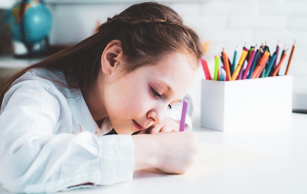 Happy cheerful child girl drawing creativity concept cute child drawing using felttip pen while sitt