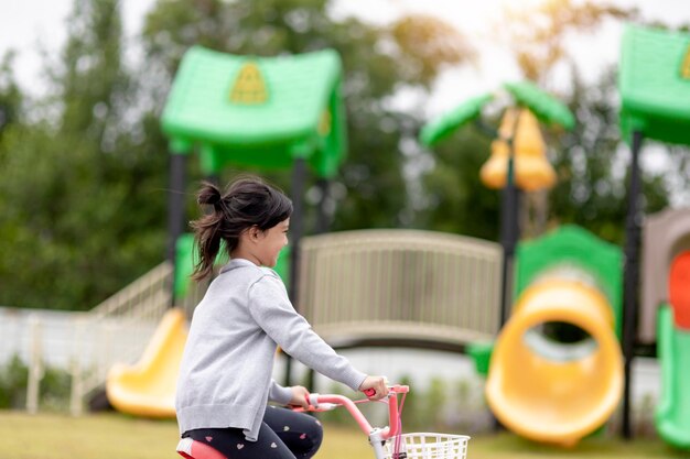 自然の中で公園で自転車に乗って幸せな陽気な子供の女の子