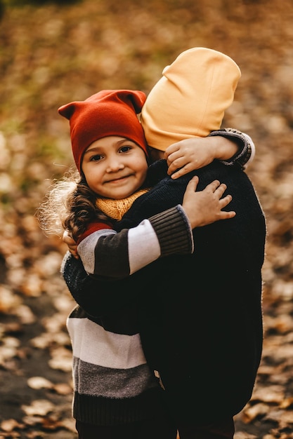 Photo happy cheerful children in warm clothes have fun walking running in autumn park playing with leaves