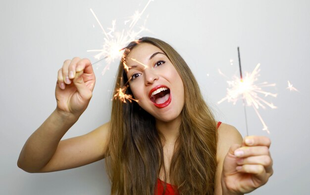 Happy cheerful girl holding bengal lights at party