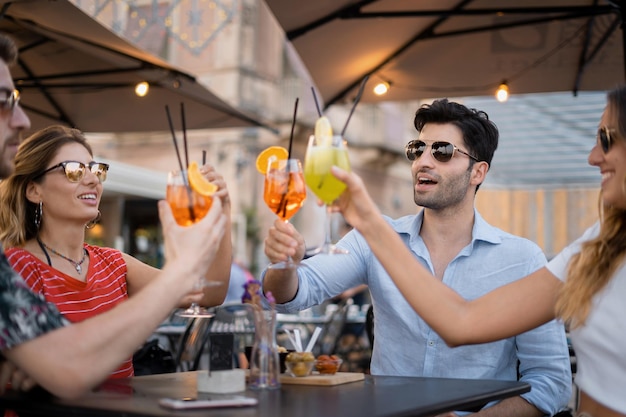 Felice e allegro gruppo di giovani amici insieme applaudire e brindare con i cocktail