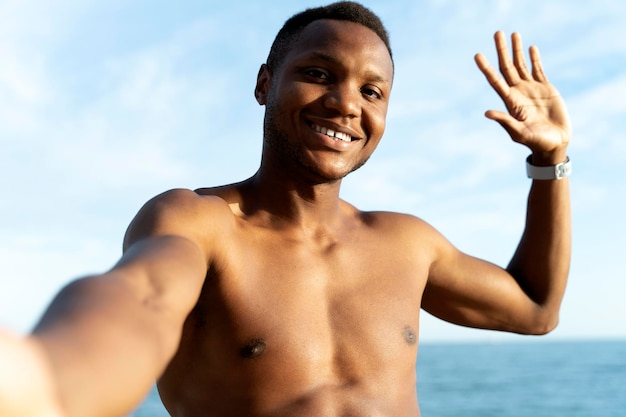 Happy cheerful joyful smiling male person making selfie in the sea under sun rays