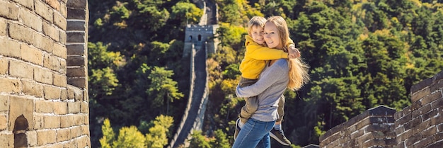 Счастливые веселые радостные туристы мама и сын у великой китайской стены веселятся в путешествии улыбаясь
