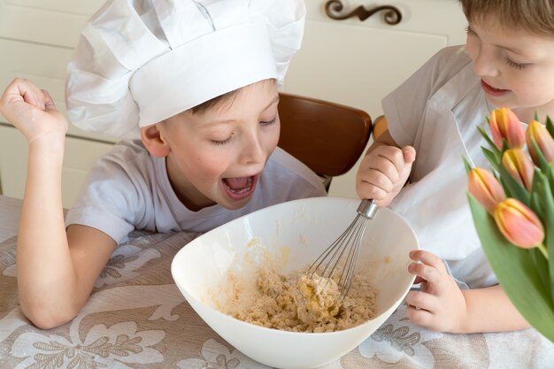 happy cheerful kids making cookie dough at home in the kitchen