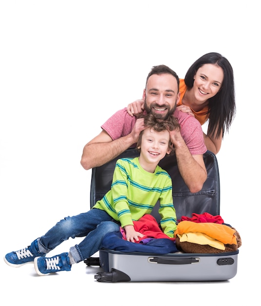 Happy cheerful parents and their son in a suitcase.