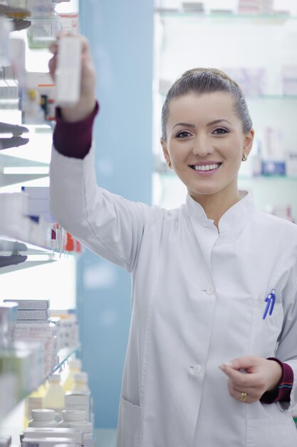 薬局の薬局に立っている幸せな薬剤師の薬剤師の女性