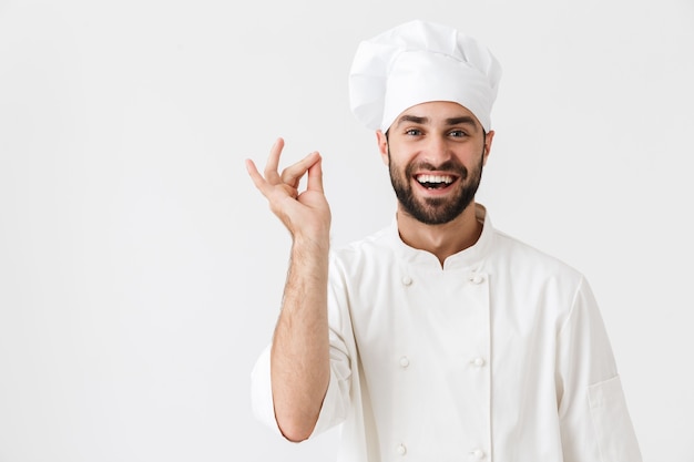 Felice allegro compiaciuto giovane chef in posa in gestualità uniforme.