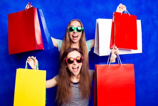 Happy cheerful sisters showing their purchases