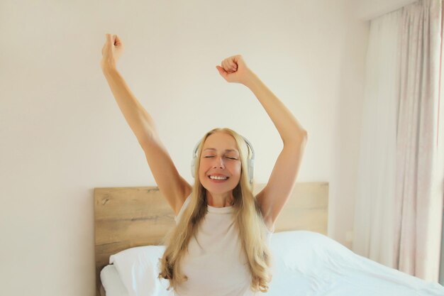 Photo happy cheerful woman listening to music with headphones having fun at home