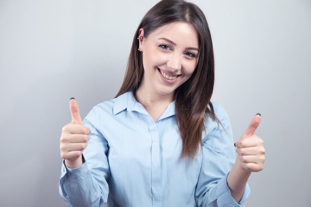 Happy cheerful woman showing thumbs up isolated gray