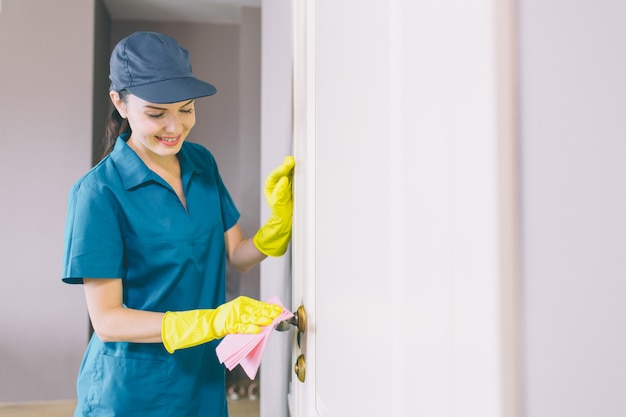 Happy and cheerful woman stands and holds the white door