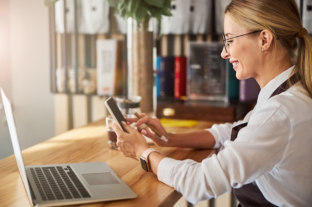 Photo happy cheerful woman in white shirt typing message on cell phone