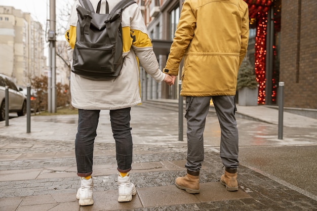 幸せな陽気で若い白人カップルは、街で屋外で一緒にデートしながら楽しんでいます