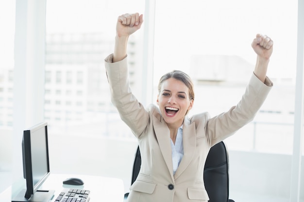 Photo happy cheering woman raising her arms sitting on her swivel chair