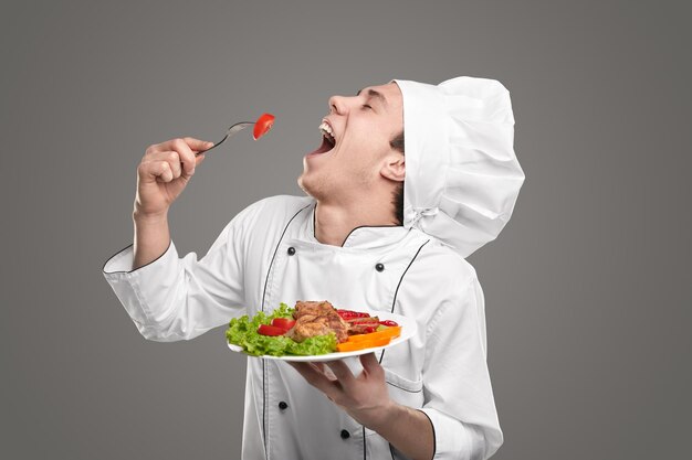 Happy chef eating tasty dish