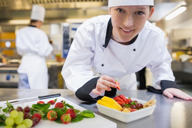 Happy chef preparing fruit salad