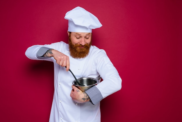 Happy chef with beard and red apron is ready to cook