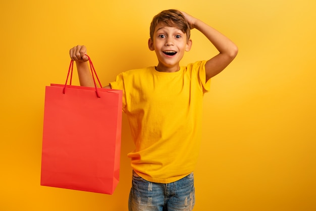 写真 幸せな子供は店の販売に驚いています。驚いた、表現。黄色の背景色