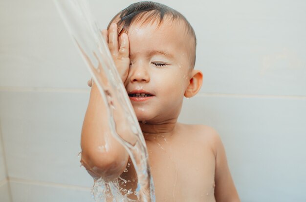 사진 머리에 물이 많이 흐르기 때문에 행복한 아이가 욕조에서 눈을 감고 목욕한다
