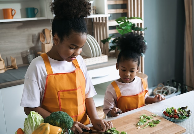 Happy child black skin with vegetable salad in kitchen