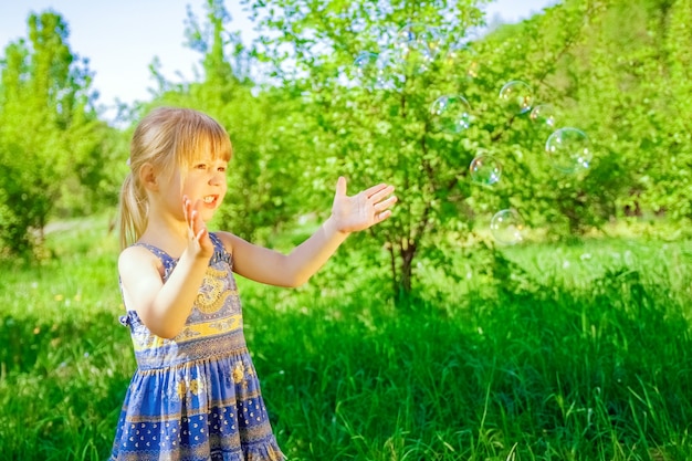 Happy child blowing bubbles on nature in pairs