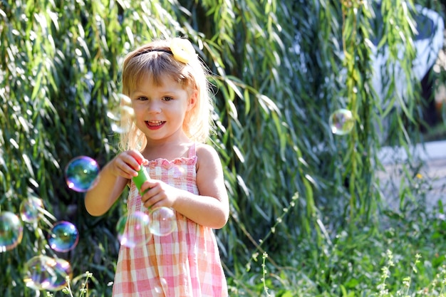 Happy child blowing bubbles in the nature park