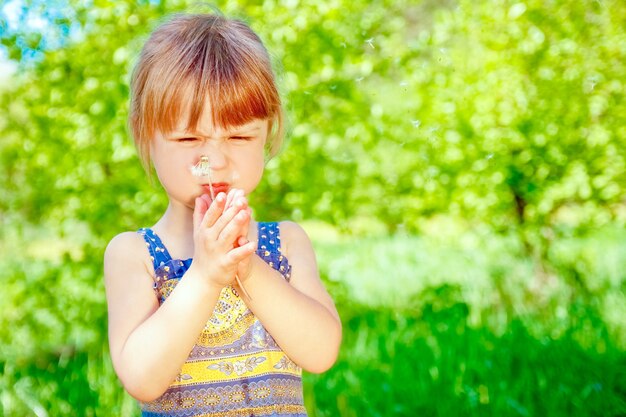 Happy child blowing dandelion on nature in the park