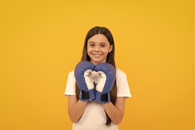 Happy child in boxing gloves on yellow background