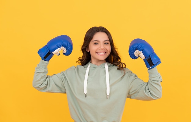 Happy child in boxing gloves on yellow background