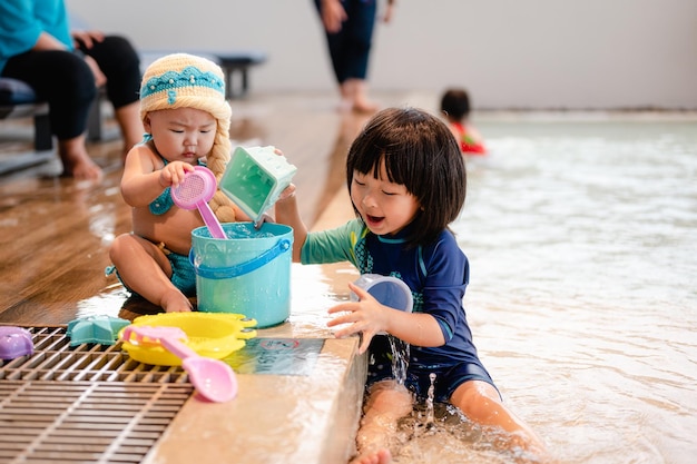 写真 幸せな子供の男の子と小さな女の子がプールでおもちゃを遊んでいるプールで楽しんでいます