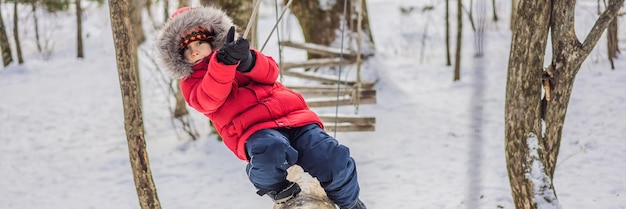 Happy child boy enjoying activity in a climbing adventure park on a winter day BANNER LONG FORMAT