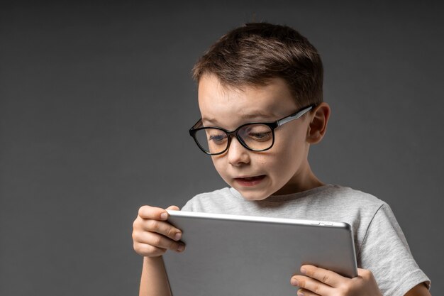 Happy child boy  holding a tablet ipade for your information on the blue background